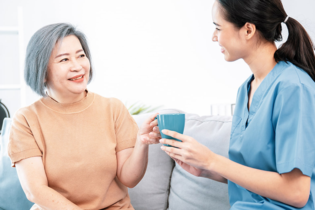 Elderly Woman Smiling with Young Nurse, Discussing Daily Care Services